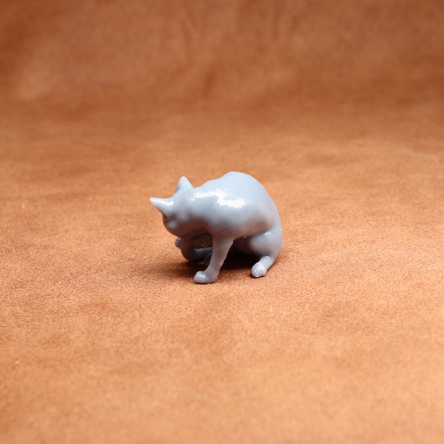 grey resin miniature cat figure on a brown surface