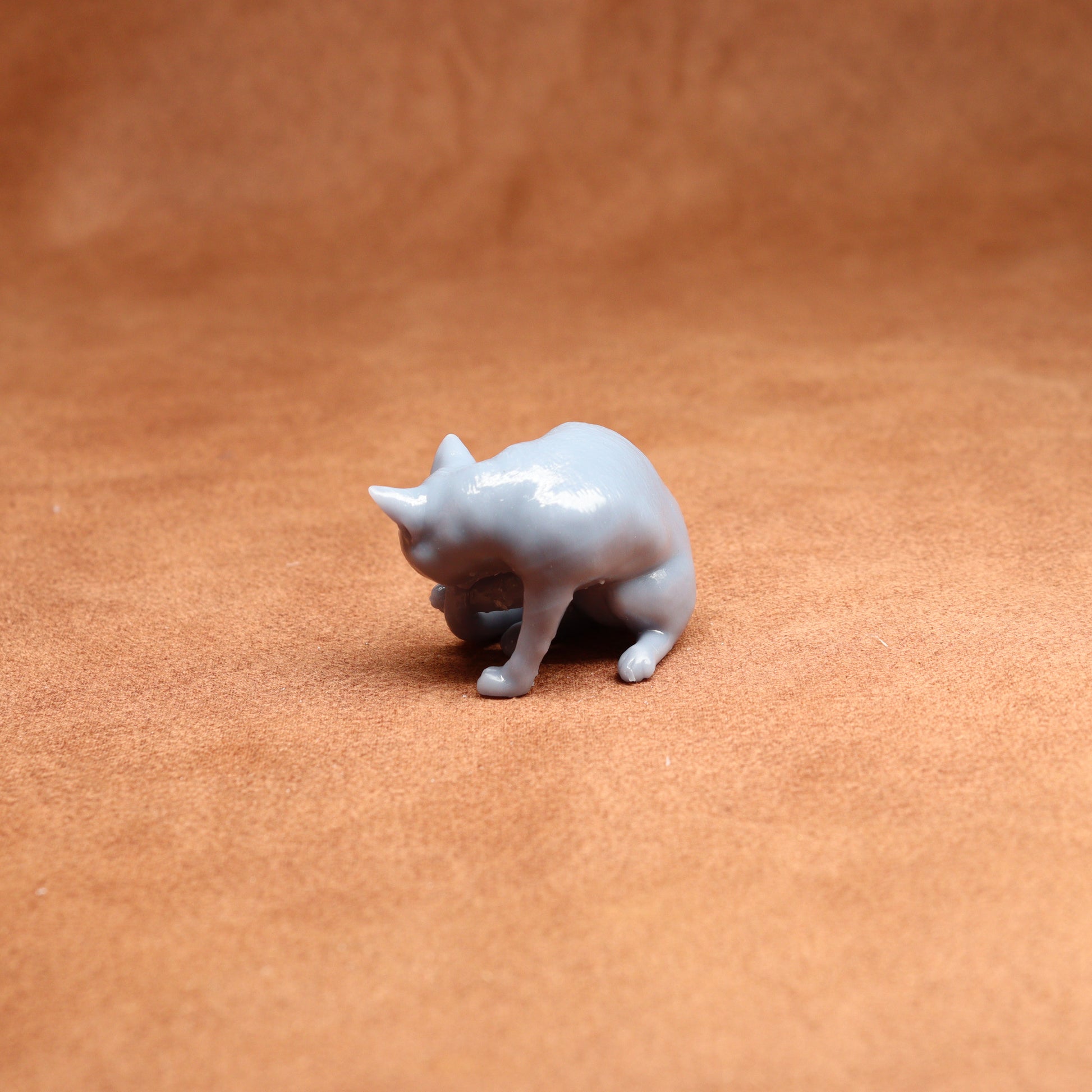 grey resin miniature cat figure on a brown surface