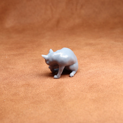 grey resin miniature cat figure on a brown surface