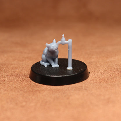 grey cat resin miniature on a black base on a brown background.