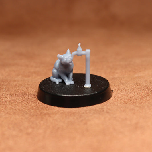 grey cat resin miniature on a black base on a brown background.