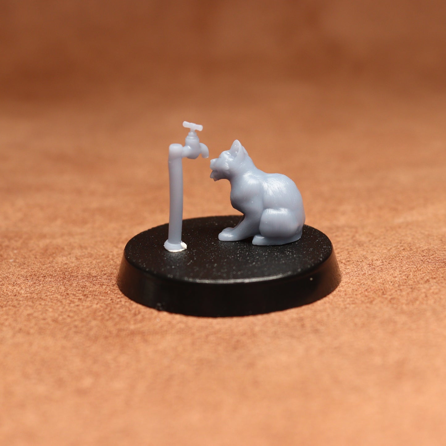 grey cat resin miniature on a black base on a brown background.