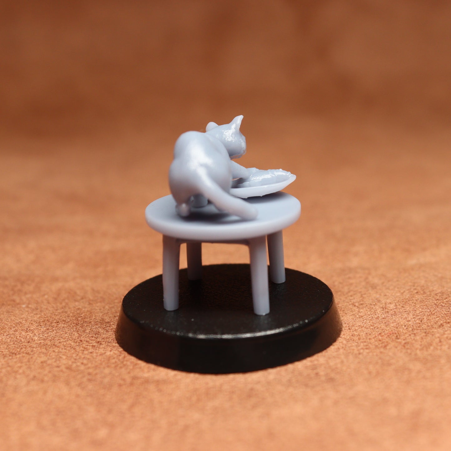 grey cat resin miniature on a black base on a brown background.
