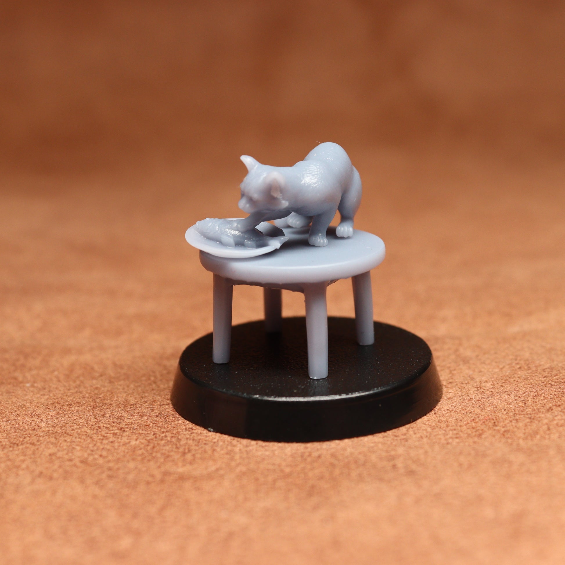 grey cat resin miniature on a black base on a brown background.