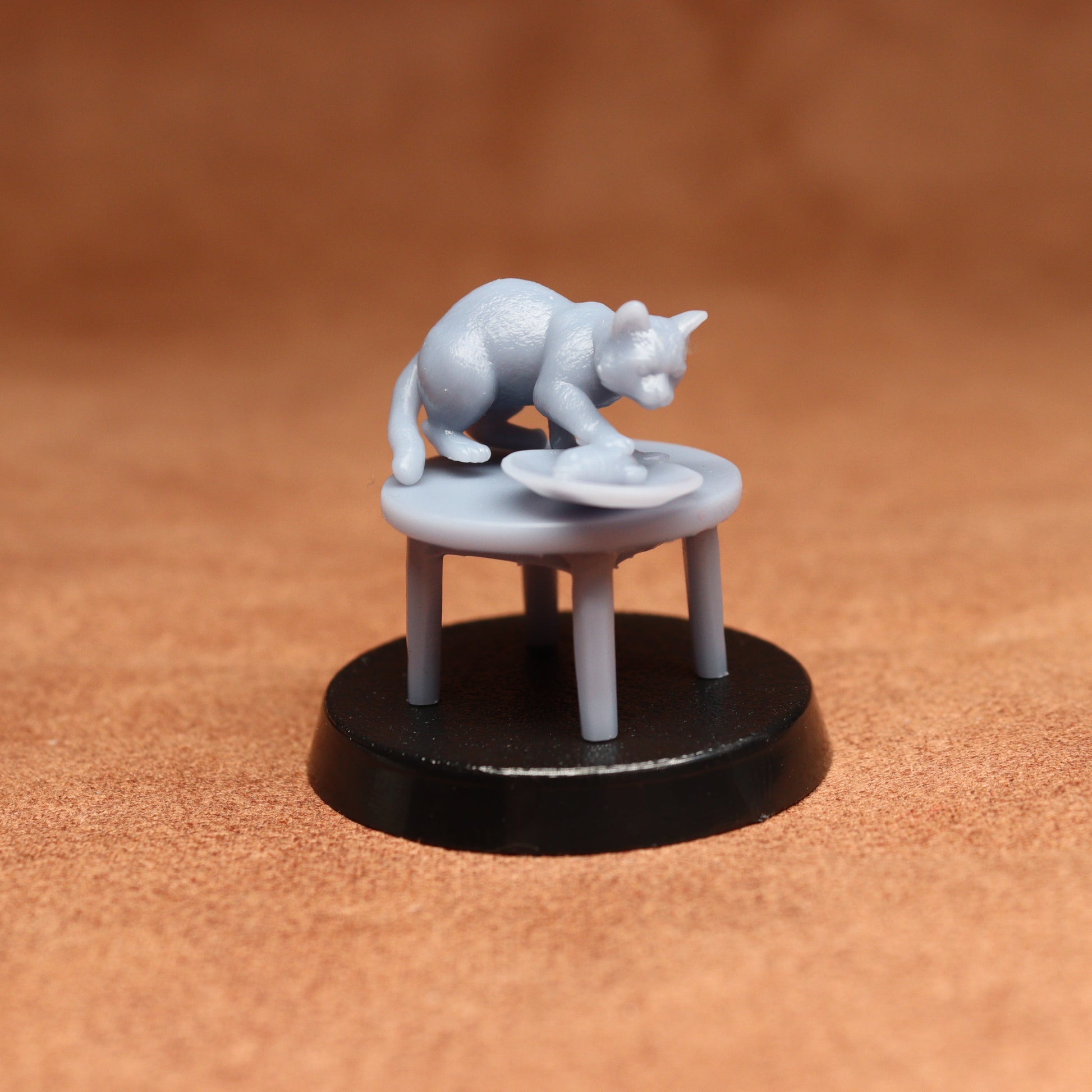 grey cat resin miniature on a black base on a brown background.