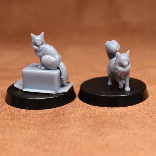 Two miniature cat figurines on black bases against a brown background