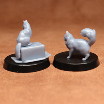 Two white cat figurines on black bases against a brown background