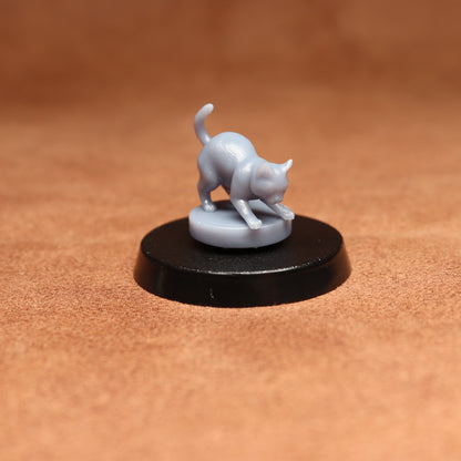 grey resin miniature cat figure on a black base with a brown background