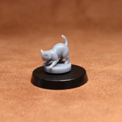 grey resin miniature cat figure on a black base with a brown background