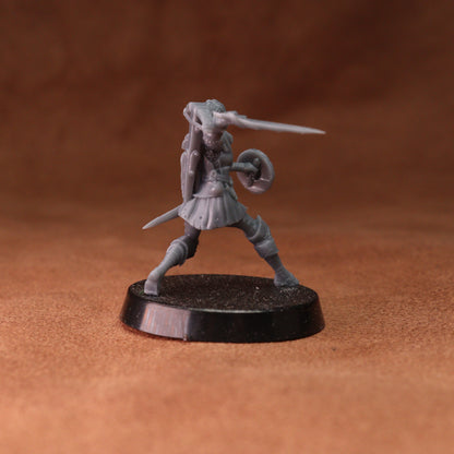 An unpainted gray fantasy warrior miniature figurine standing on a round black base against a warm brown textured background.
