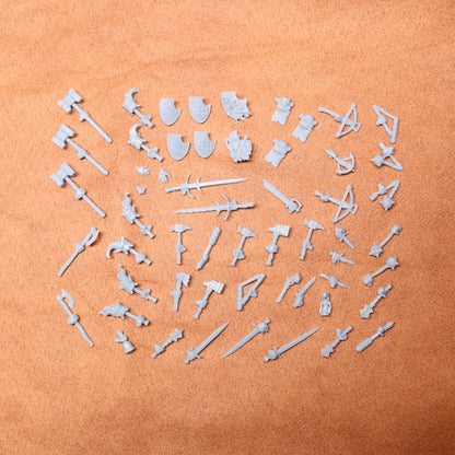 Collection of white resin toy figures and weapons on a brown surface