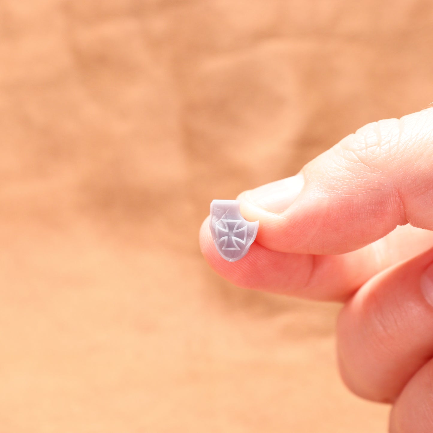 Small decorative object held between fingers against a blurred background