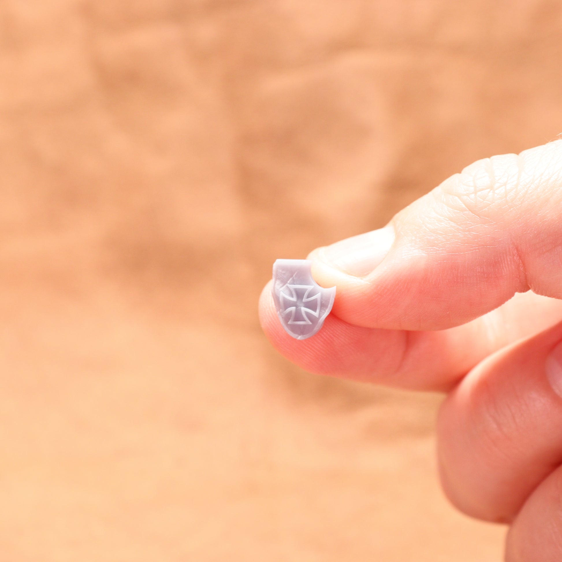 Small decorative object held between fingers against a blurred background