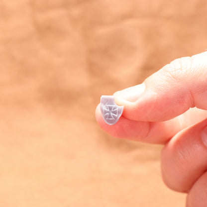Small decorative object held between fingers against a blurred background