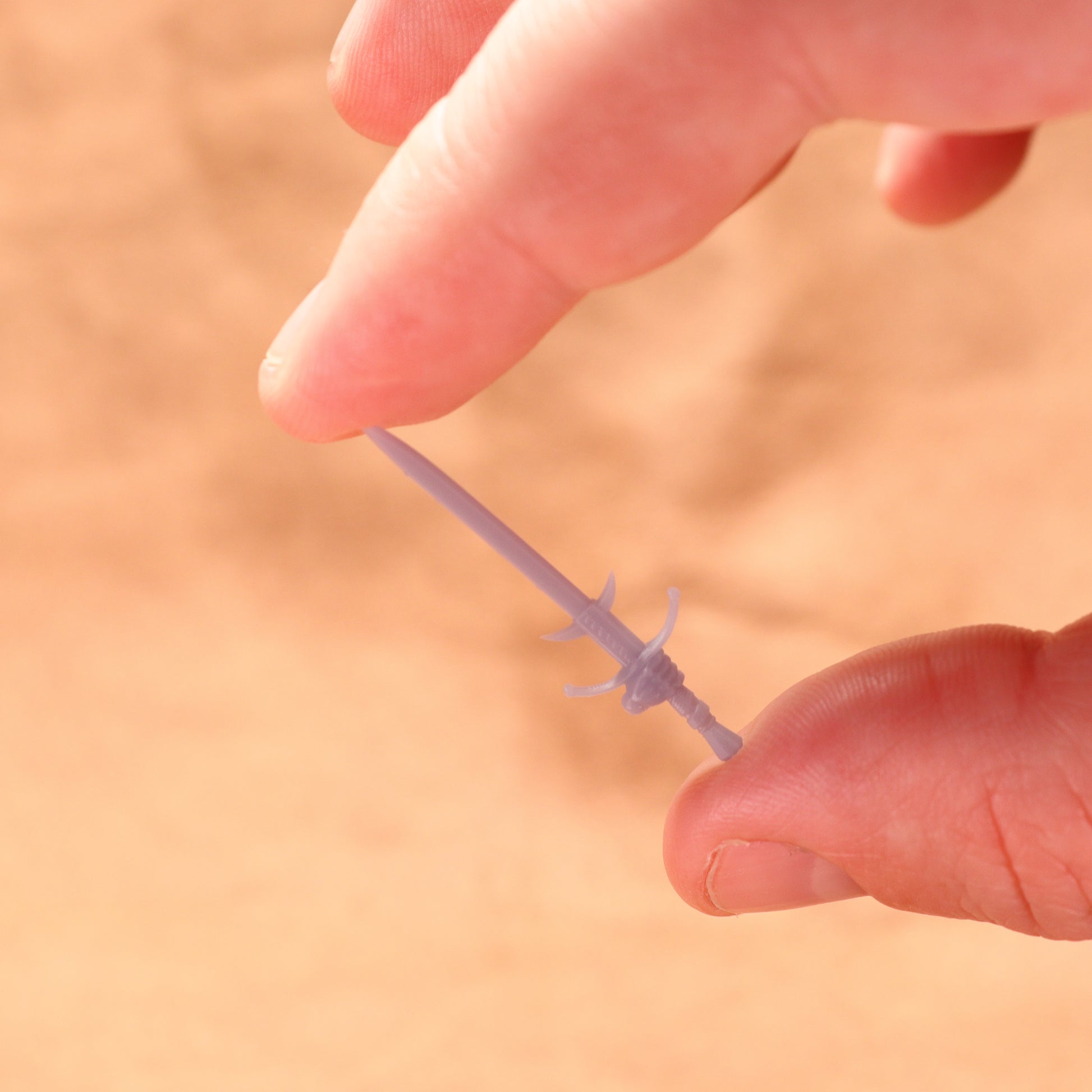 Hand holding a small metallic object against a blurred background