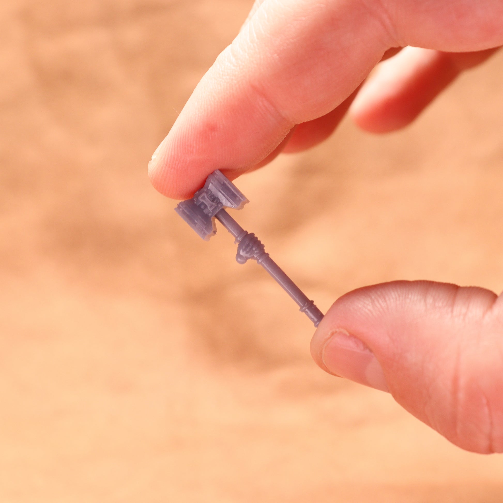 Small purple key figurine held between fingers against a blurred background