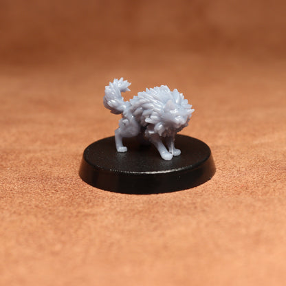 grey cat resin miniature on a black base on a brown background.