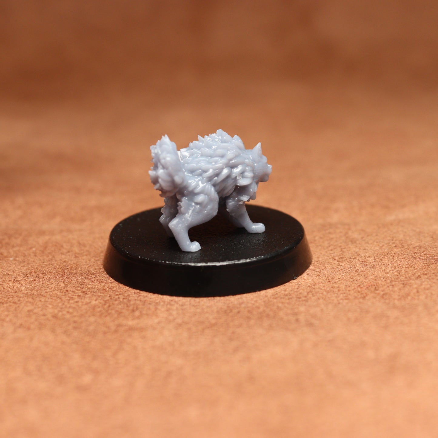 grey cat resin miniature on a black base on a brown background.