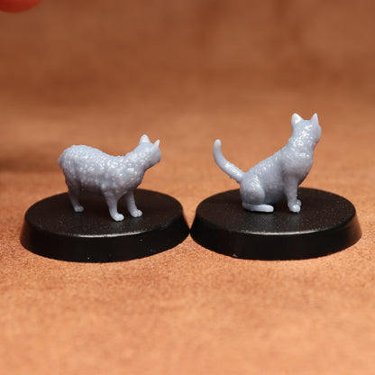 Two miniature cat figurines on black bases against a brown background