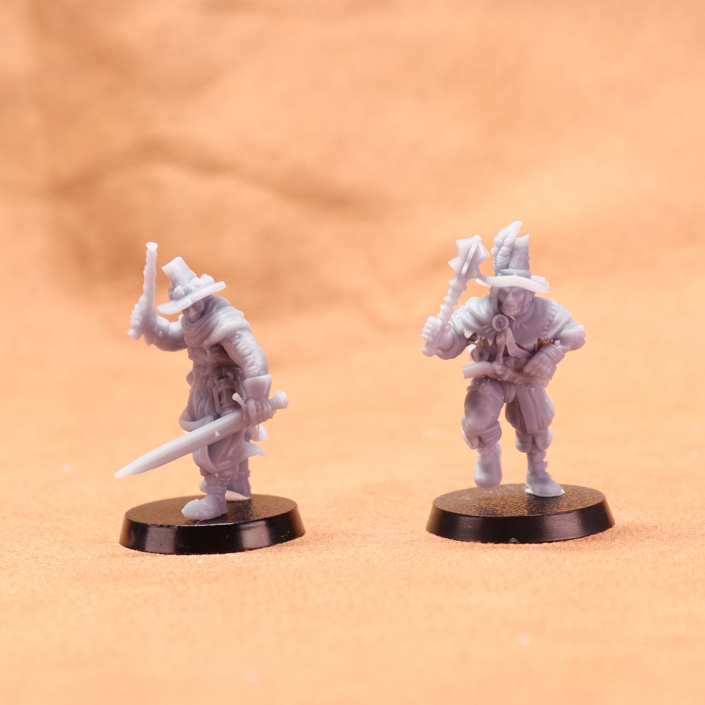 Two miniature figurines on black bases against a beige background