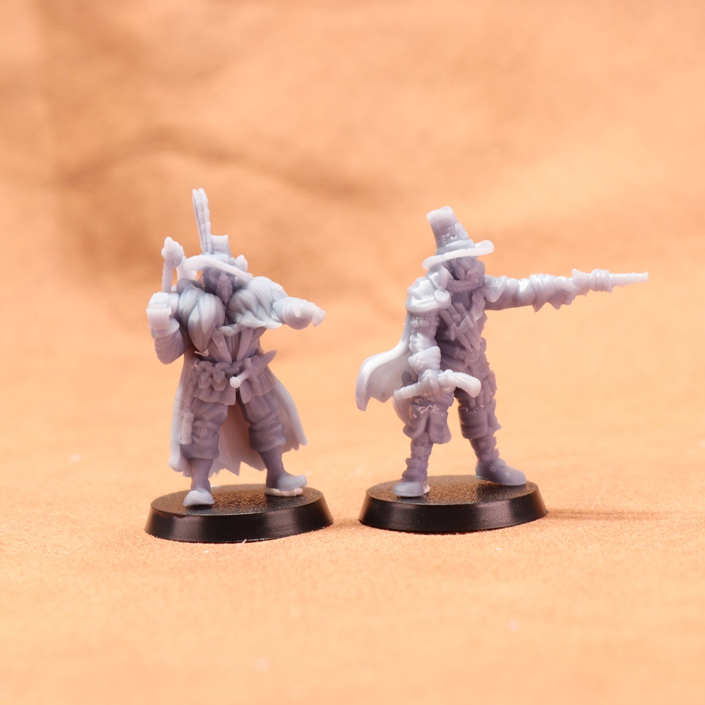 Two miniature figures on round bases against a beige background