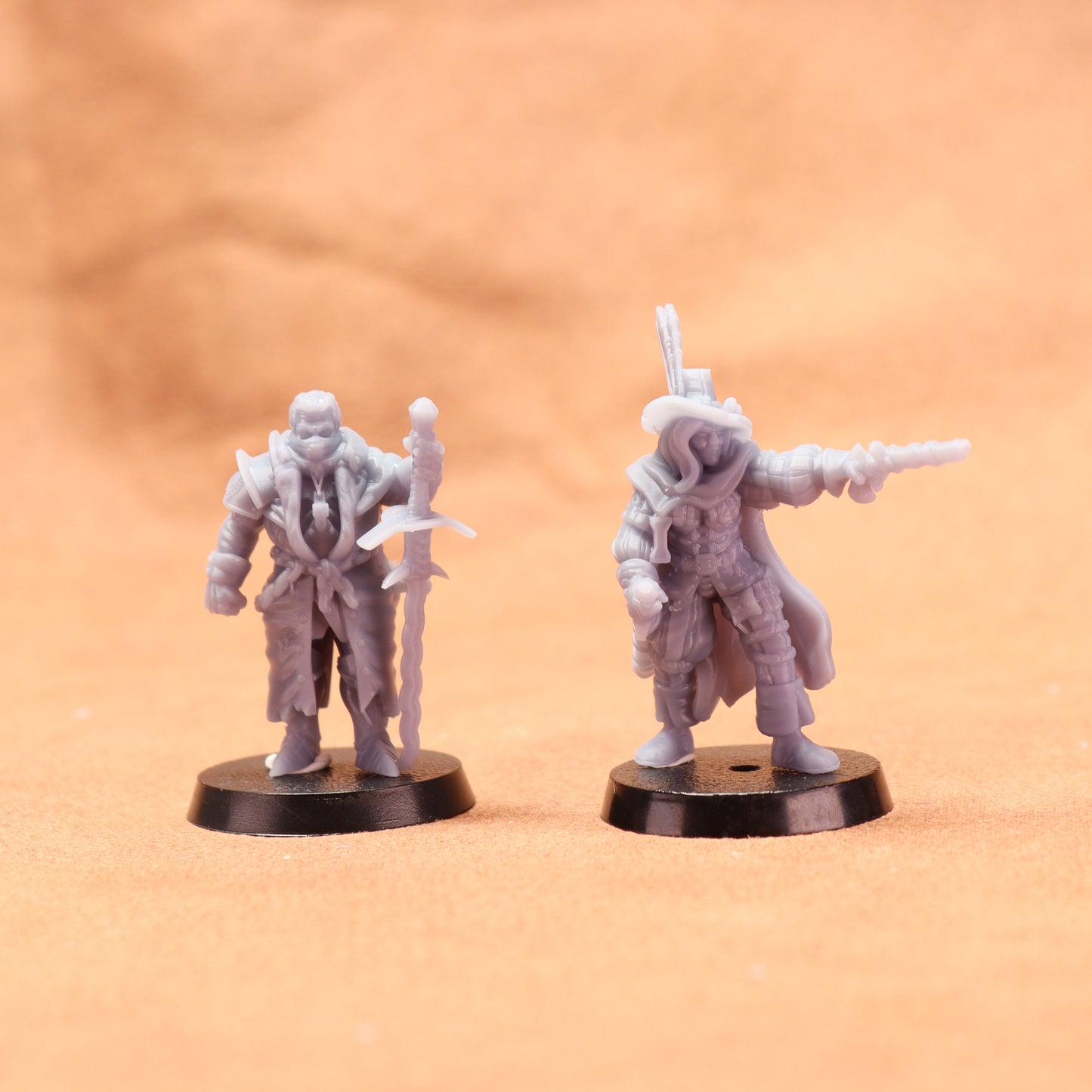 Two miniature figures on black bases against a beige background