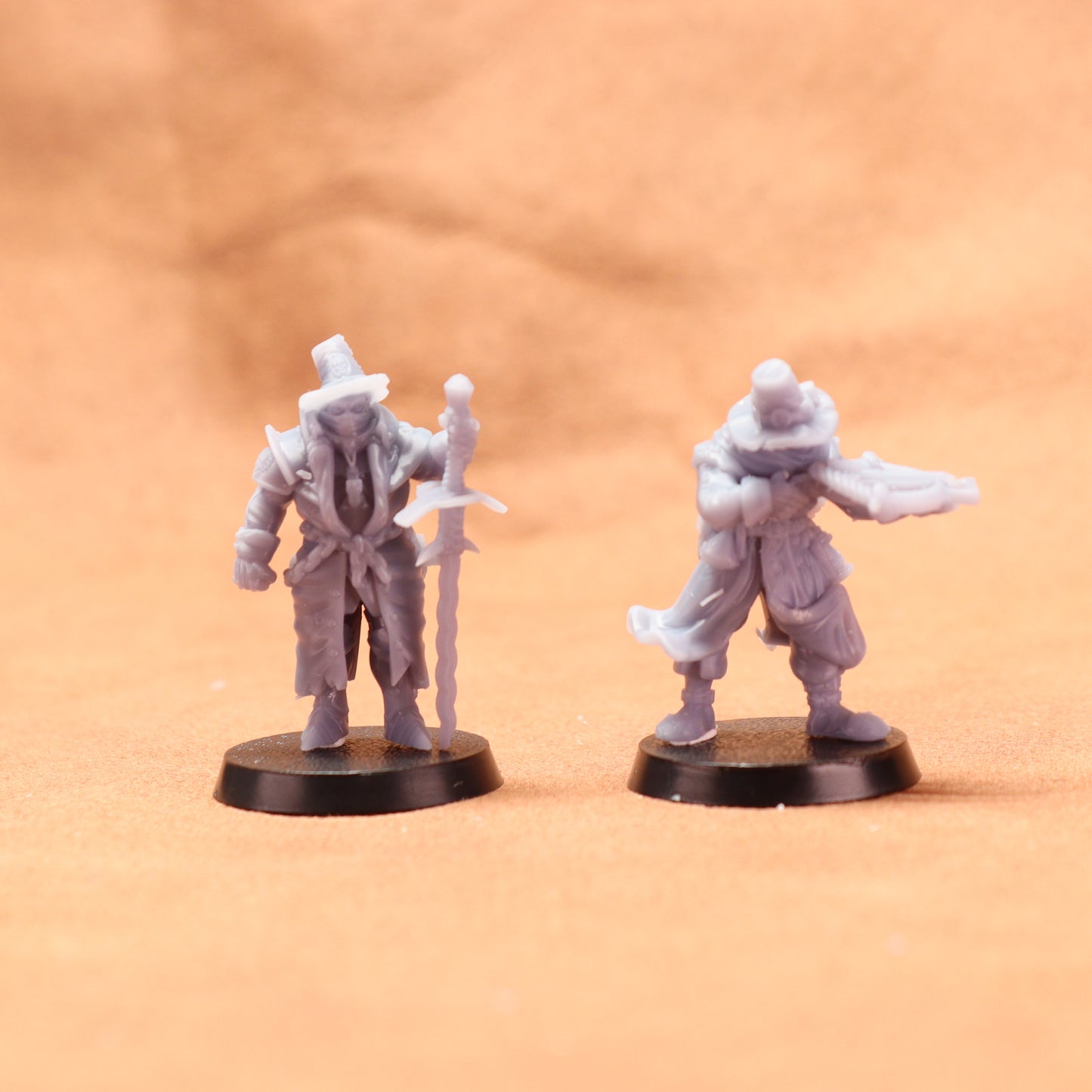 Two miniature figures on round bases against a beige background