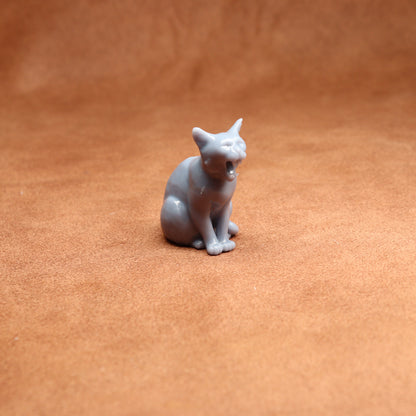 Small white cat figurine on a brown textured surface