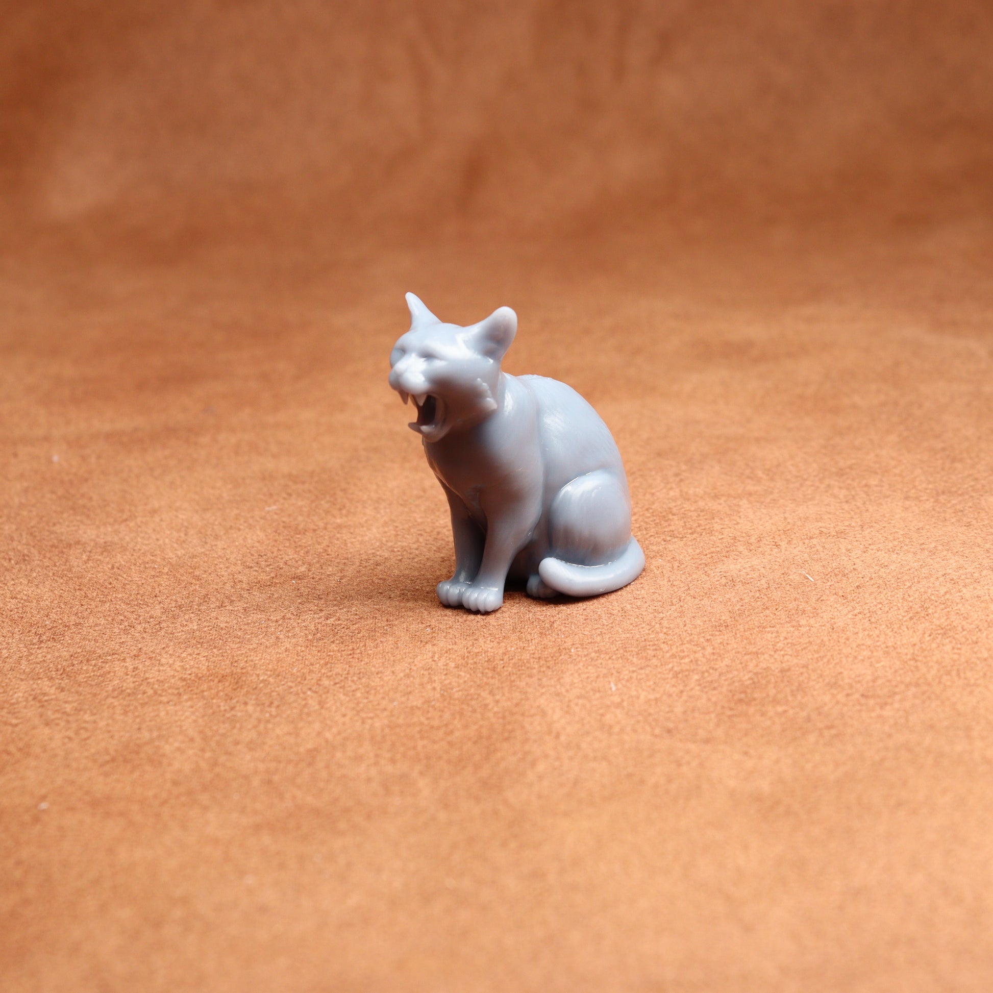 grey resin cat miniature figure on a brown surface