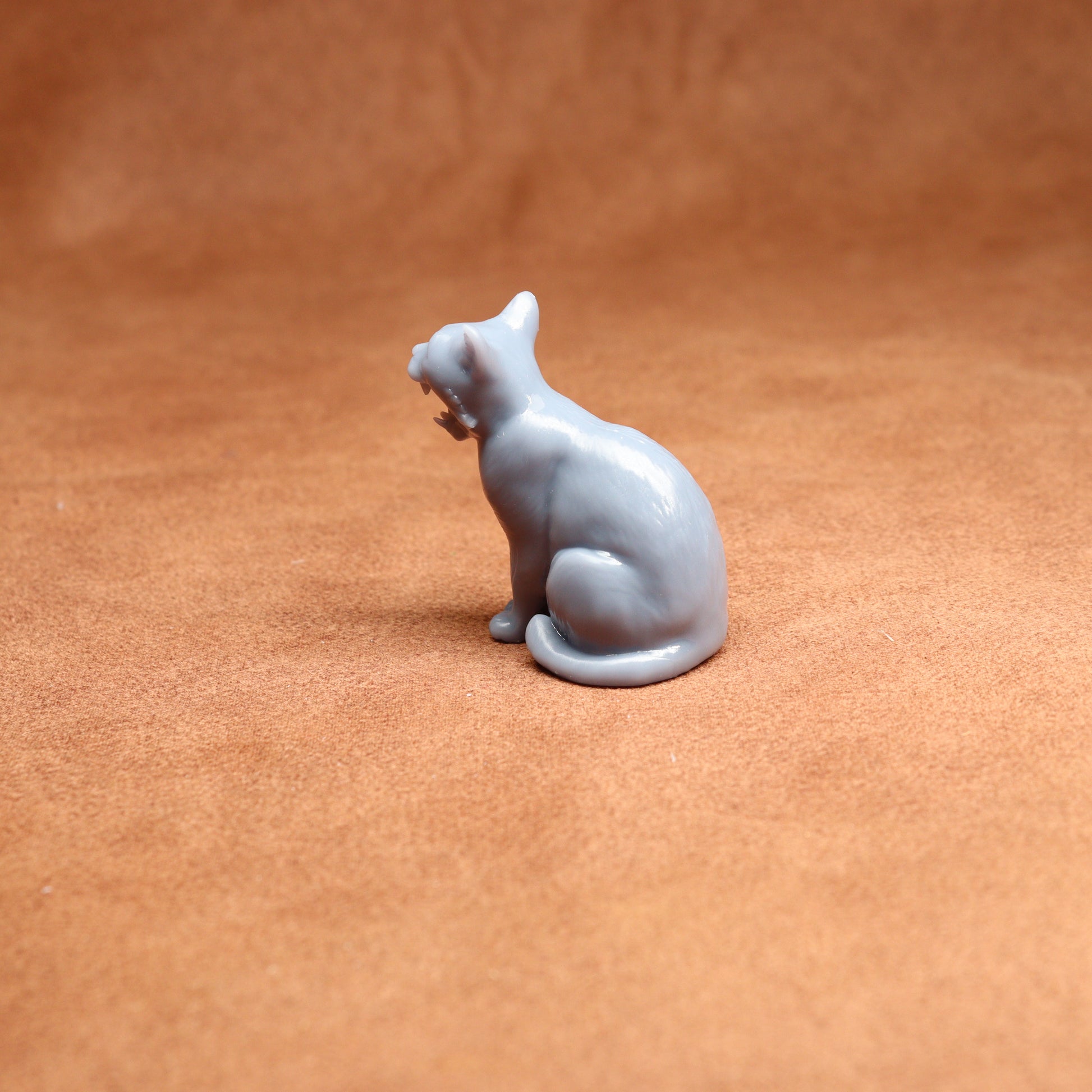 grey resin cat miniature figure on a brown surface