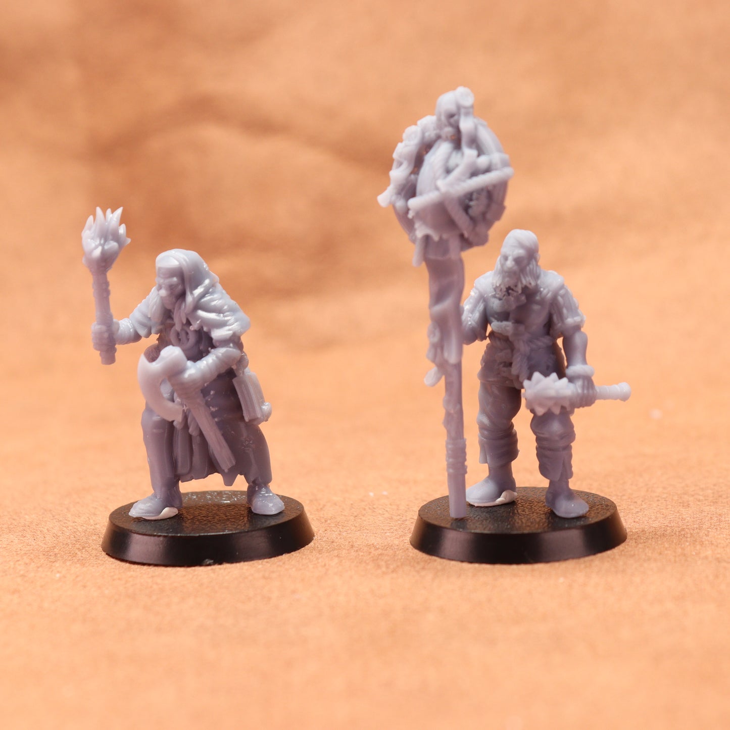 Two miniature figures on black bases against a brown background
